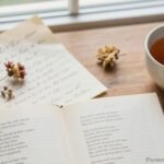 Open poetry book on a wooden table with handwritten notes and a cup of tea — best poems to memorize collection